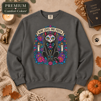 Load image into Gallery viewer, Pepper Comfort Colors crewneck sweatshirt with Nine Lives, One Fiesta Día de Muertos black cat design in a fall flat lay
