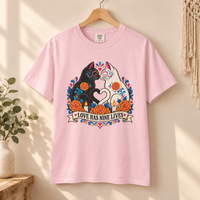 Load image into Gallery viewer, Love Has Nine Lives Brights Day of the Dead black cat t-shirt in Blossom on a wooden hanger, Comfort Colors
