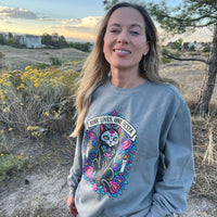 Load image into Gallery viewer, Woman wearing a Grey Nine Lives, One Fiesta Day of the Dead black cat sweatshirt outdoors at golden hour
